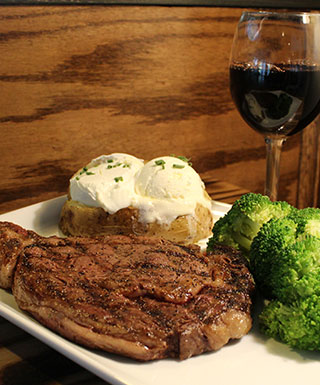 Journey steakhouse with steak, broccoli, baked potato, and glass of wine at Argosy Casino Alton.