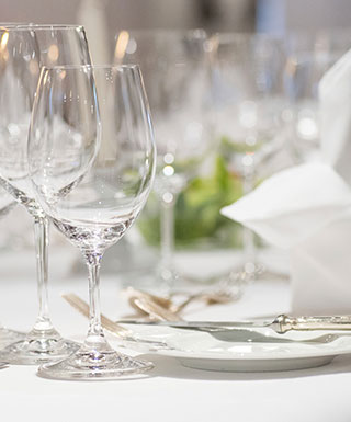 Event tables setup with glasses, plates, and napkins for Argosy Casino Alton Event and Meeting Center.