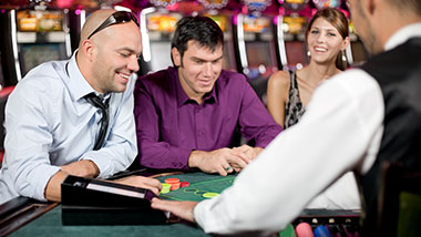 Two men playing blackjack while a woman looks on at Argosy Casino Alton.